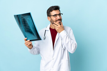 Professional traumatologist holding radiography isolated on blue background thinking an idea