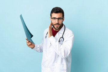 Professional traumatologist holding radiography isolated on blue background whispering something