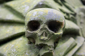An old sculpture of a human skull on a grave to depict death, the end of life.