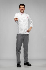 cooking, culinary and people concept - happy smiling male chef in jacket pointing finger to camera over grey background