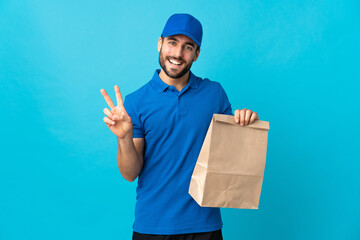 Delivery man with beard isolated on blue background smiling and showing victory sign