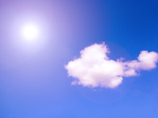 The white sun shines in the blue sky near the clouds. Natural background