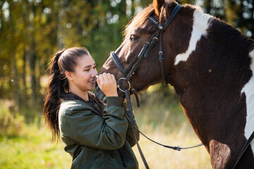 Obraz premium Cute girl talking with her horse after a joint walk in the background of the forest.