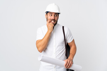 Young architect man with helmet and holding blueprints isolated on white background nervous and scared