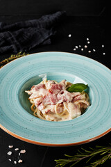 chinese noodles with vegetables and meat in a blue plate on black background