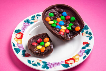Cracked stuffed mm's easter egg on a white plate with colorful fruit prints on a pink background.