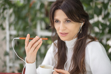 A beautiful young European woman with headphones and a phone in her hands is listening to a new...