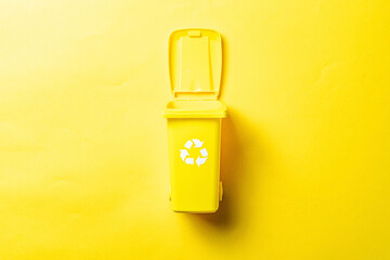 Bin icon. Container for disposal garbage waste and save environment. Yellow dustbin for recycle plastic trash isolated on yellow background.