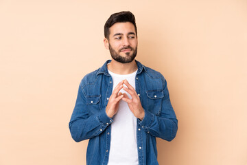 Caucasian handsome man isolated on beige background scheming something