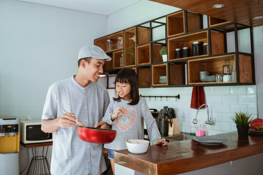portrait of happy asian father and daughter cooking together in modern kitchen