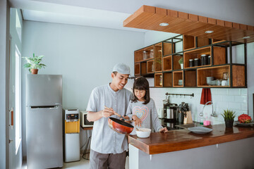 portrait of happy asian father and daughter cooking together in modern kitchen