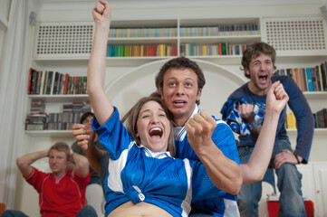 Ragazzi felici dopo un gol mentre guardano la partita di calcio in televisione