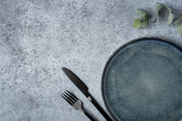 An empty plate and cutlery on a gray table. Top view.