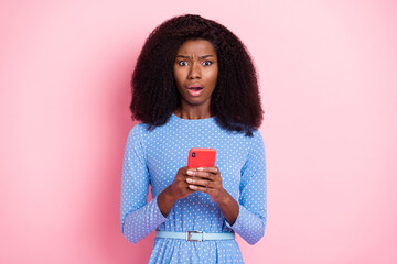 Photo of speechless lady hold phone look camera open mouth wear blue dotted dress isolated pink color background