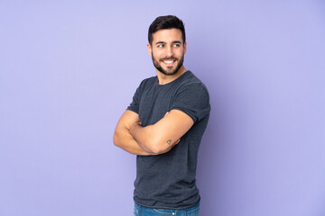 Caucasian handsome man looking to the side and smiling over isolated purple background