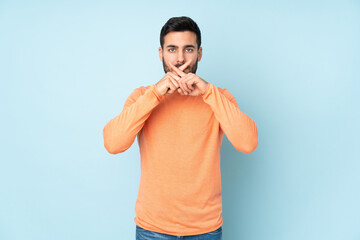Naklejka premium Caucasian handsome man showing a sign of silence gesture over isolated blue background