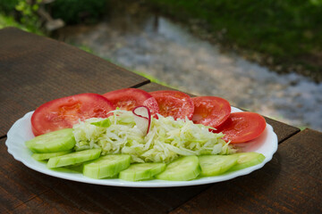 Light and healthy Traditional Serbian countryside salad - bashta salata with fresh garden cucumber, coleslaw, tomato and olive oil
