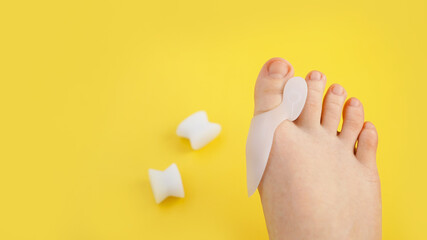 Silicone finger separator. Orthopedic thumb corrector. Legs on a bright yellow background.