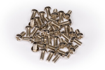 Pile of small cross recessed machine screws on white surface