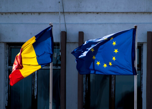 The flag of Romania and the flag of the European Union hoisted in front of a building