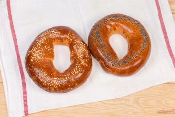 Two ring shaped bread rolls sprinkled sesame and poppy seeds