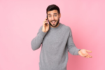 Caucasian handsome man over isolated background keeping a conversation with the mobile phone with...