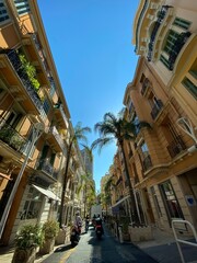 Fototapeta na wymiar Enge Gasse in Monaco mit Palmen bei Sonnenschein und Blauem Himmel, Monte-Carlo, Roller 