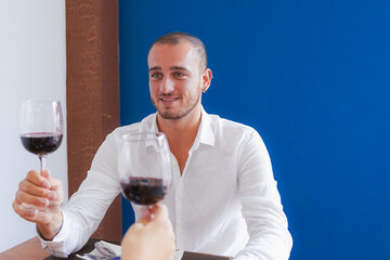 Happy couple dining and drinking wine at restaurant. Man and woman drinking a good red wine. Food, drink and proposal married concept.