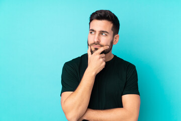 Caucasian handsome man isolated on blue background having doubts and with confuse face expression