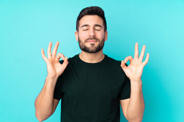 Fototapeta premium Caucasian handsome man isolated on blue background in zen pose