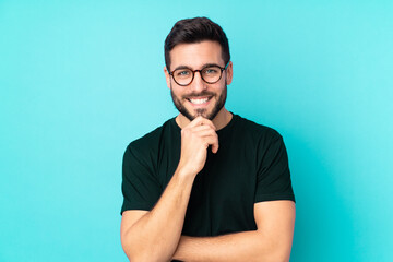 Caucasian handsome man isolated on blue background with glasses and smiling