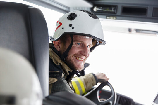 Smiling firefighter driving fire engine