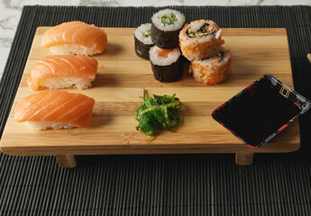 Delicious sushi on a marble table with a wooden plate.
Chopsticks next to a sushi plate.