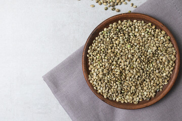 There is a clay bowl with hemp seeds on the concrete surface.