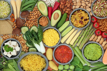 Healthy vegan food for vitality and fitness with bean curd, vegetables, legumes, nuts, dips, grains, oatmeal crackers and pasta. Health foods that lower cholesterol and blood pressure. Top view.