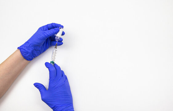 hands in medical blue gloves with a syringe and a vaccine on a white background