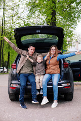 Happy family with  son on  background of  trunk of  SUV