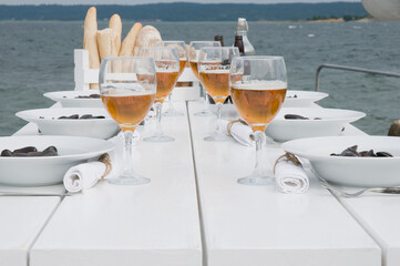 Table set by the sea with oysters and beer.