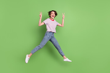 Full length body size view of pretty cheerful amazed girl jumping showing v-sign isolated over...