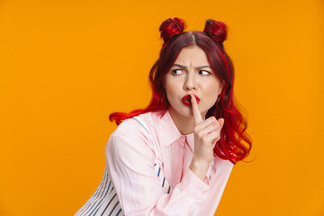 Displeased beautiful girl with red hair showing silence gesture