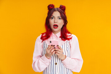 Shocked girl with red hair expressing surprise and using mobile phone