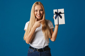 Happy beautiful girl showing and pointing finger at gift box