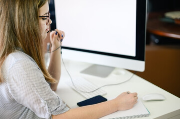 Young woman with headphones working, learning, talking on computer