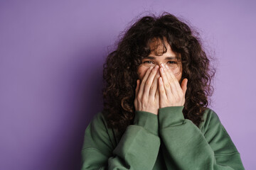 Happy beautiful curly girl smiling and covering her face with hands