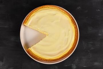 Top view of traditional New York cheesecake with cream cheese and sour cream layer with one slice...