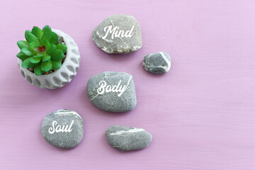 zen stones with the words Mind body soul. purple wooden background