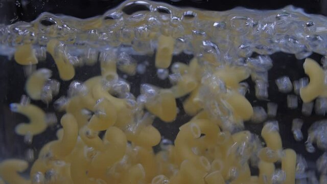 pouring macaroni pasta into pot with water 4k