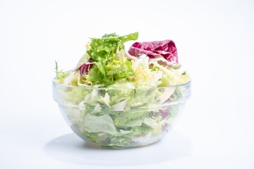 Lettuce salad in transparent bowl isolated on white.