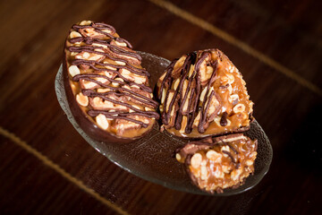Stuffed chocolate easter egg with peanut on a glass stand with a wooden background.