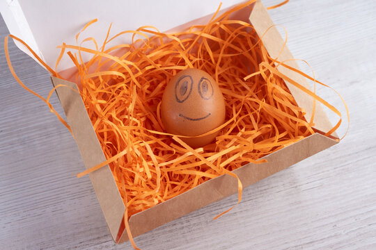 Smiling egg in a cardboard box.